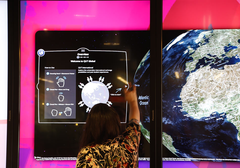 Graphic design, student interacting with QUT HiQ Kelvin Grove touch screen wall with digital content by Maya Walker
