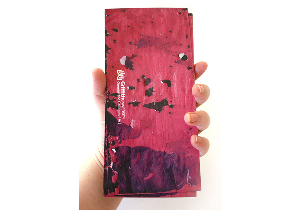 Graphic design, hand holding stack of DL print invitations to QCA Graduate Exhibition 2012 by Maya Walker